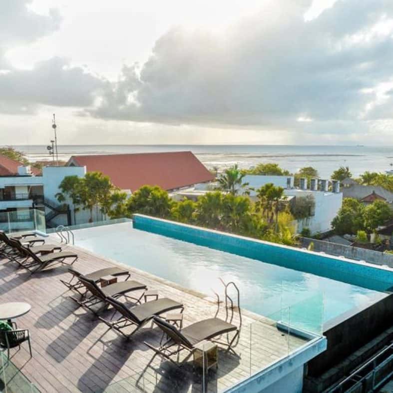Rooftop pool with sun lounges over looking the beach at Saner Bali
