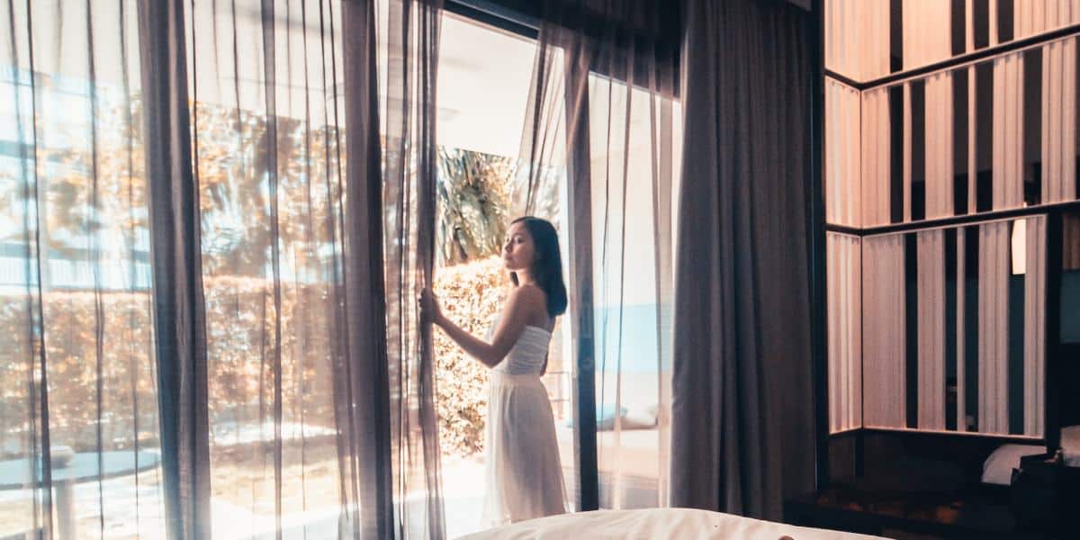 a good looking young lady looking at the window of her villa in Bali