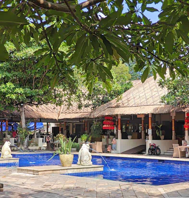 Mercure Sanur, a modern beachfront hotel with a large swimming pool, surrounded by lush greenery and palm trees, offering a relaxing tropical getaway.