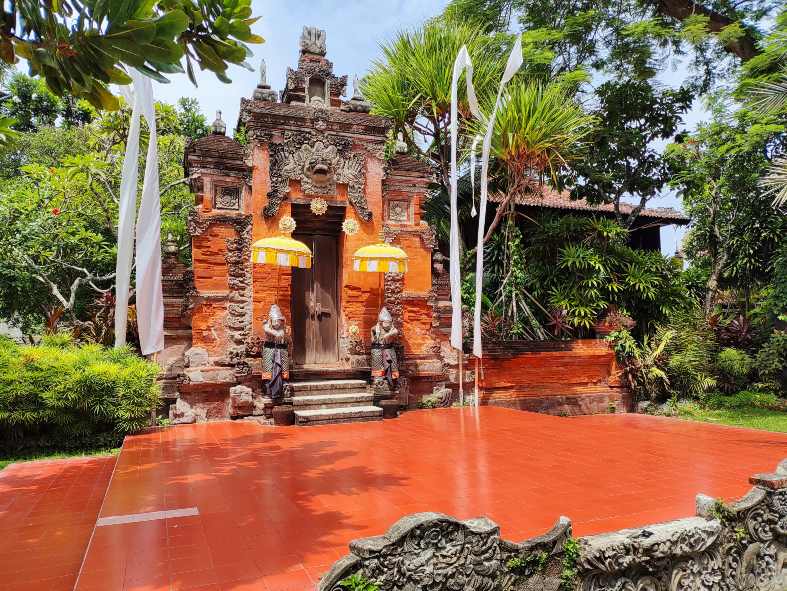 a traditional Bali gate with a red floor and a red floor with white flags